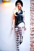 Person wearing a black leather outfit with a unique design on a white wall.