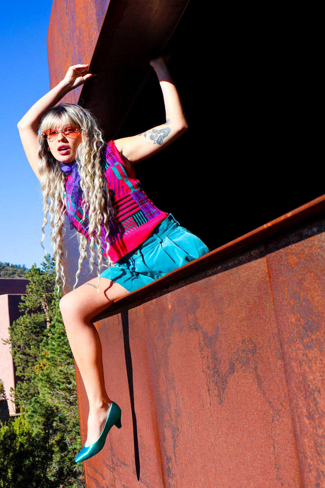 Person sitting on a large metal sculpture with a scenic background